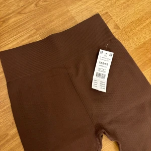 Bruna ribbade leggings - Säljer ett par snygga bruna ribbade leggings i storlek XXS/XS. De är superstretchiga och bekväma, perfekta för både vardag och träning. Högmidjade för en skön passform och stilren look.