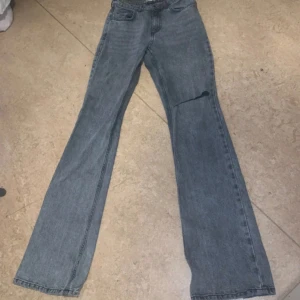 Gråa Gina tricot utsvängda perfect jeans - Gråa Gina tricot utsvängda perfect jeans populärt hål vid knät. De är jätte snygga men tyvärr passar de inte längre. Jag är 1,66 och de är perfekt längd.