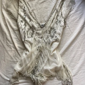 Volang blus - Volang blus med mycket detaljer som sitter snyggt på. Silvriga detaljer i mönster och volanger gör toppen väldigt ”feminin” och går att styla på många sätt.