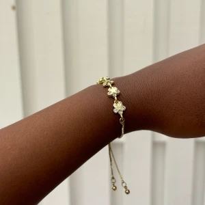 Glamoröst Armband med Stjärn- och Blomdetaljer - Ett glittrande armband i rostfritt stål, dekorerat med vackra stjärn- och blomdetaljer i kubisk zirkonia.