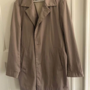Hugo Boss trenchcoat  - Säljer min trenchcoat från Hugo Boss. Lite skrynklig då den hängt i garderoben denna säsong. Samt en liten fläck på ena bröstet (se bild). Nypris 2500kr.