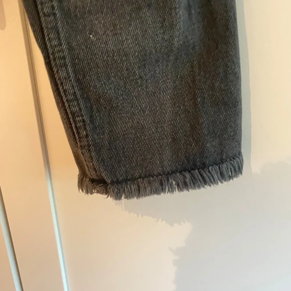 Säljer ett par svart/grå jeans från NAKD. De har en fransad kant vid bensluten, klassisk design med en rak passform och slutar ovanför ankeln. Jeansen är i bra skick och passar till de flesta outfits!. Jeans & Byxor.