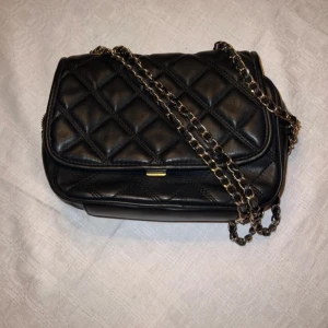 Svart väska   - Fått av min kusin så lite oklart hur använd men själv bara ett fåtal gånger.  Super smart band att man kan justera om man vill ha längre eller kortare! Flera fack i och dragkedja.