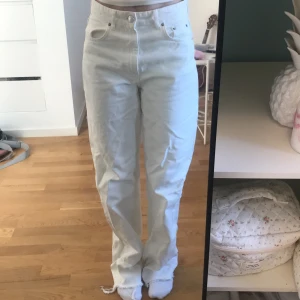 Vita jeans med hög midja - Säljer ett par vita jeans med hög midja. De har en straight passform och är perfekta för både vardag och fest. Jeansen har klassiska fem fickor och knappar framtill. Superbekväma och stilrena!