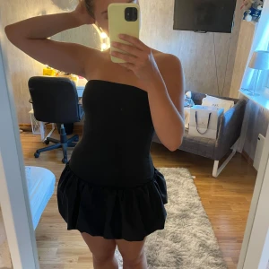 Svart kort klänning - En svart kort klänning. Klänningen trendar över nätet och är en snygg fest klänning. En tajt klänning med en puff detalj längst ned. I storlek S.