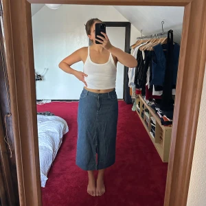 Jeanskjol - Midikjol i jeans med slits framtill. Sitter som en mid-rise på mig som är en storlek M. Kommer nog sitta snyggt lågmidjat om man är en mindre storlek!