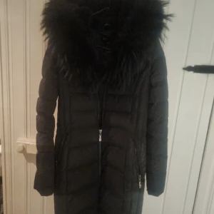 Hollies vinterjacka - Säljer nu min fina Hollies vinterjacka med stor luva och äkta päls. Jackan fäljer kroppen jätte fint. Inga hål , fläckar eller liknande.  Färg svart Storlek 36  Köpt på hollies i barkaby för 4999 kr  Priset kan diskuteras