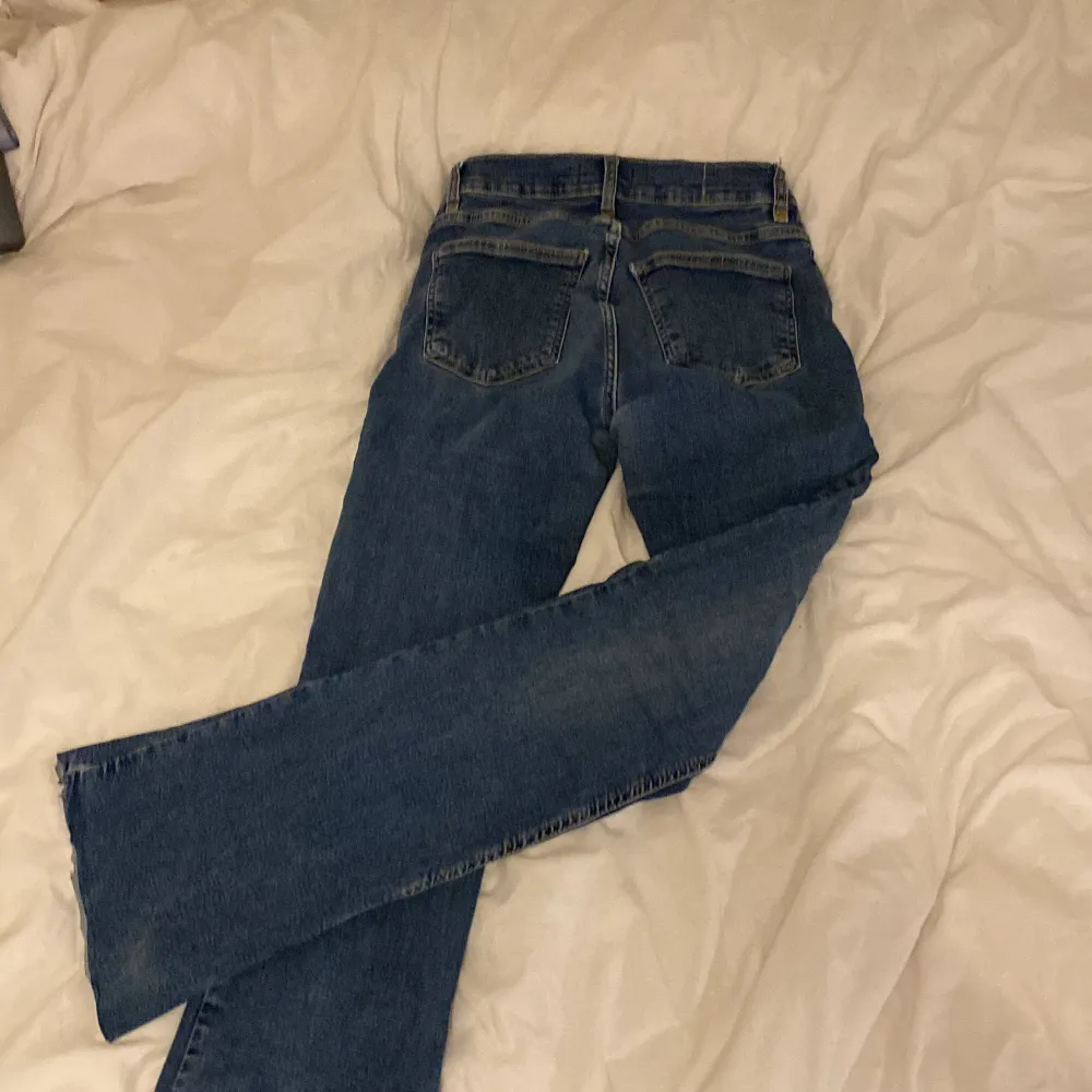 Säljer ett par klassiska blå jeans från Gina Tricot i storlek 38. De har en snygg bootcut fit och är perfekta för vardagsbruk. Jeansen har en knapp och dragkedja framtill. De är i bra skick och redo för en ny ägare! Pris kan diskuteras. Jeans & Byxor.