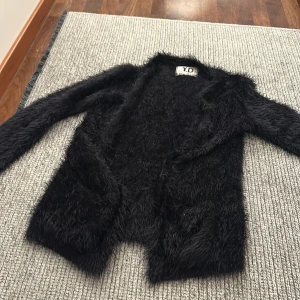 Svart pälsjacka från Y.D - Säljer en supermjuk och fluffig svart pälsjacka från Y.D. Perfekt för att hålla sig varm och stilren under kyliga dagar. Jackan har långa ärmar och en öppen design utan knappar eller dragkedja. Passar perfekt till både vardag och fest!
