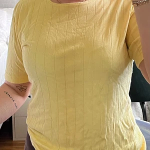 Gul ribbad topp - Säljer en superfin gul ribbad topp med trekvartsärm. Den är i ett mjukt och bekvämt material som sitter skönt på kroppen. Passar till vardags 