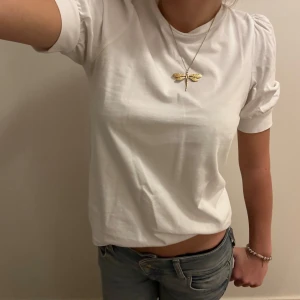 Rosa och vit topp från Aware by Vero Moda - Säljer två söta toppar från Aware by Vero Moda i storlek XS. Den ena är ljusrosa och den andra är vit. Båda har korta ärmar med en liten puffdetalj som ger en gullig touch.