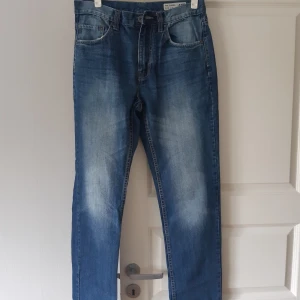 Blå jeans från 157 - Säljer ett par klassiska blå jeans från märket 157. De har en snygg tvätt med lite ljusare partier fram och bak. Jeansen har en normal passform och är perfekta för vardagsbruk. De är i bra skick och redo för en ny ägare!