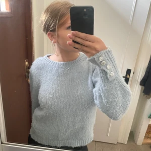 Ljusblå stickad tröja - Säljer denna eleganta stickade tröja från only då den inte riktigt passar min stil. Den har ett litet ”puff” vid axlarna samt små stenar vid handlederna som gör det väldigt elegant. Tröjan har används sparsamt men köptes på sellpy för 200kr