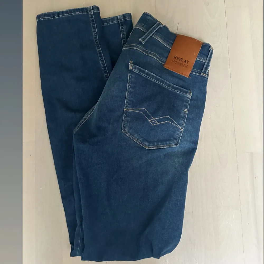 Säljer ett par snygga blå jeans från Replay, modell Anbass. De har en cool slitningseffekt och är i en straight passform. Perfekta för en avslappnad stil!. Jeans & Byxor.