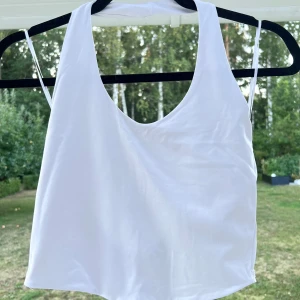 Vit halterneck-topp - En vit halterneck-topp från Bikbok. Använd max 3 gånger 💞 Superskönt material! Gjord av polyamid och elastan ☺️  Längd: 25,5 cm Byst: 74 cm