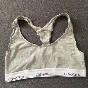 Grå sporttopp från Calvin Klein - Säljer en grå bomullstopp från Calvin Klein. Den är ärmlös och har en bekväm passform med brottarrygg med logotypen runt nederkanten. 🤍 Skickas eller hämtas i Linköping.📬
