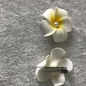 Plumeria Hawaiian Frangipani Skumblommor  - Snygga vita hårklämmor formade som blommor med en subtil gul nyans i mitten och dekorerade med pärlor. Perfekta för att ge en elegant touch till din frisyr. Klämmorna är lätta att fästa och håller håret på plats.  Pris 59kr/2st med pärlor, 50kr/2st utan pärlor , helt ny 