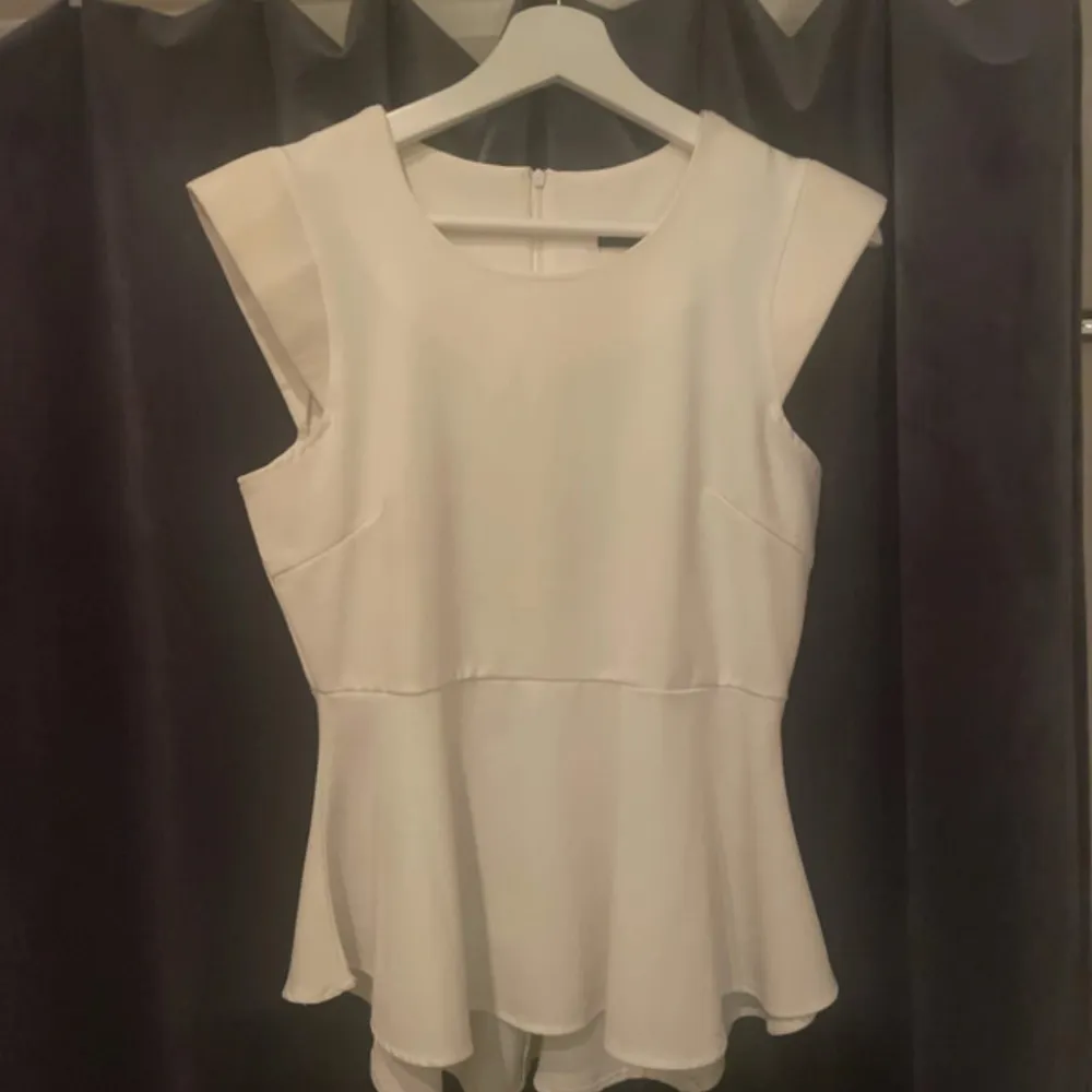 Säljer en stilren vit blus från VILA i storlek S. Blusen har en elegant design med ärmlös stil och en lätt utsvängd nederdel. Dragkedja på ryggen. Axlarna på blusen är fylliga. Blusen är använd 2 gånger.. Puserot.