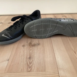 Nike fotbollsskor - Säljer ett par svarta Nike fotbollsskor med grå sula och snörning. Perfekta för inomhusfotboll.