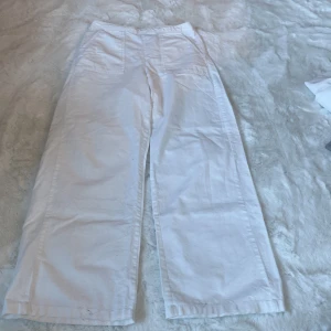 Vita linnebyxor från Kappahl - Säljer ett par vita byxor från Kappahl i storlek 164. De har en liten fläck längst ner på höger ben. Byxorna har en loose passform och är tillverkade i ett lätt och bekvämt material. Perfekta för en avslappnad stil.