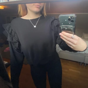 Svart tröja med volangdetaljer - Säljer en stilren svart tröja med volangdetaljer på axlarna🖤