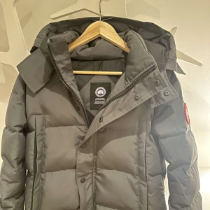  Canada Goose wyndhamn parka - Säljer en fräsch Canada goose Wyndham i färgen grå. Den är sparsamt använd och har inga skador. Storlek xs päls ingår. Pris 1800kr