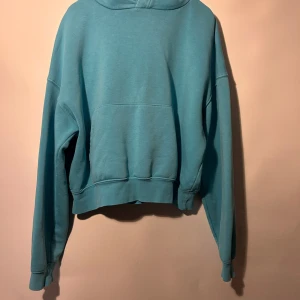 Cropped hoodie från zara - Turkosfärgad hoodie med långa ärmar och en avslappnad passform. Den har en justerbar huva och en praktisk känguruficka framtill. Passformen är cropped, storlek S, ok skick, lite urtvättad