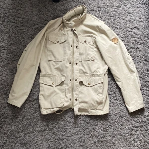 Beige Fieldjacket från Fjällräven - Säljer en beige jacka från Fjällräven med dragkedja och knappar. Jackan är i toppskick✅ Nypris ca 3000