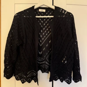 Svart stickad kofta JDY - Säljer en svart stickad kofta från JDY med ett vackert hålmönster. Koftan har långa ärmar och en öppen design utan knappar. Aldrig använd💖