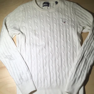 Vit stickad tröja från GANT - Säljer en stilren vit stickad tröja från GANT i stretchig bomull. Tröjan har ett klassiskt kabelstickat mönster och rund halsringning. Perfekt för en avslappnad och snygg look. 🧶pris kan diskutera👍