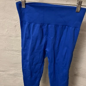 Träningstajts  - Snygga blå byxor med hög midja och ribbade detaljer. Perfekta för träning eller en avslappnad dag. Materialet är stretchigt och bekvämt.