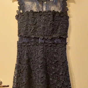 Mörkblå spetsklänning - Mörkblå spetsklänning med blommigt mönster och transparenta detaljer. Perfekt till vår/ sommar.