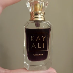 Kayali Vanilla 28 Parfym - Säljer en elegant parfym från Kayali med doften Vanilla 28. Flaskan är genomskinlig med en mörk vätska och har en lyxig, facetterad kork i guld. Perfekt för den som älskar varma och söta dofter. Köpt hösten 24 från sephora. 10 ml ursprungligen se bild för mängd kvar!