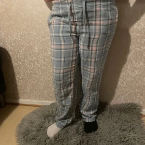 Rutig mjukisbyxa i blått och rosa - Mysiga mjukisbyxor med rutigt mönster i blått och rosa. Byxorna har en bekväm passform med snörning i midjan för justerbarhet. Perfekta för en avslappnad dag hemma. Tryck inte på köp direkt utan hör av dig till mig!!