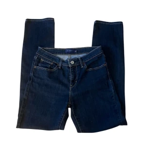Mörkblå Levi’s jeans  - Snygga mörkblå jeans från Levi's med klassisk femficksdesign och knappgylf. Perfekta för en avslappnad stil. Levi's logotyp syns på bakfickan.