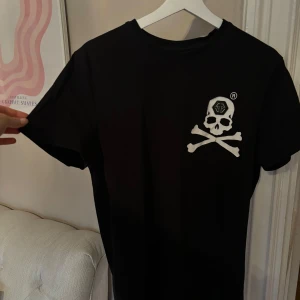 Svart t-shirt med dödskalle från Philipp Plein - Snygg svart t-shirt från Philipp Plein med ett coolt dödskalletryck på bröstet. Perfekt för en edgy look. Tillverkad i mjukt material för extra komfort.