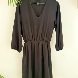 Svart klänning, H&M - Snygg svart klänning från H&M med v-ringning och trekvartsärmar. Den har en elastisk midja som ger en fin passform. 