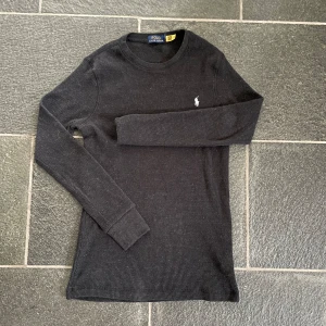 Svart ribbad tröja från Polo Ralph Lauren - Snygg svart ribbad tröja från Polo Ralph Lauren med långärmad design. Är ett perfekt plagg för att ha en grisch outfit🤑🤑 och är perfekt för en stilren look. Passar bra till jeans och en laidback outfit.🥵Qr koden funkar och den är autentiskt.
