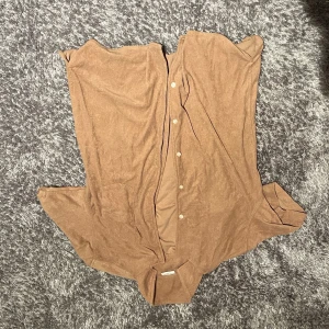 Brun frotté piké med knappar - Säljer en stilren brun frotté piké  med knappar. Perfekt för en avslappnad look. Skjortan har en klassisk krage och är tillverkad i ett mjukt material. Nypris 799kr