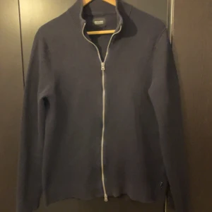 Mörkblå stickad kofta med dragkedja - Säljer en stilren mörkblå stickad kofta från Zalando. Den är i okej skick och storlek M