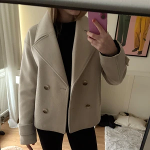 Beige kappa från Kappahl - Snygg beige kappa från Kappahl. Använd fåtal gånger. Har en liten defekt på ena armen (visas på sista bilden) köpt för 899kr och säljer för 300kr