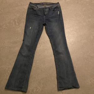 Blå bootcut jeans från Vanilla Star - Snygga blå bootcut jeans från Vanilla Star med låg midja. De har en klassisk femficksdesign och slitna detaljer för en trendig look. Innerbenslängd: 75 Midjemått: 36