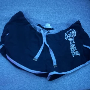 Svarta shorts med grå detaljer - Snygga svarta shorts med grå midja och snörning. Har en cool tryckt text på sidan. Perfekta för en avslappnad stil.