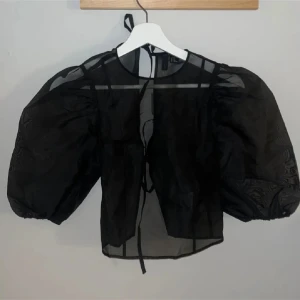 Svart blus med puffärmar - Säljer en svart genomskinlig blus med puffiga kortärmar och knytning. Storlek Xs, använd 1 gång💖