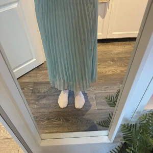 Ljusgrön plisserad kjol från H&M - Säljer en elegant ljusgrön plisserad kjol från H&M. Kjolen är tillverkad i 100% polyester och har en luftig och flödande design som passar perfekt för varmare dagar. Den har en elastisk midja för extra komfort.