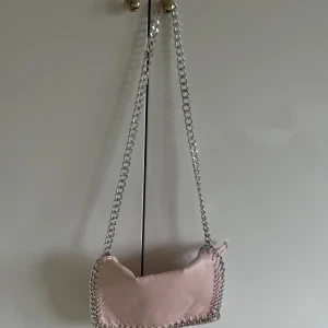 Rosa axelväska från Tiamo - Säljer en snygg rosa axelväska från Tiamo med silverkedja och dragkedja.Väskan är i storlek medium. Köpt för 450kr på scoretts hemsida. Går inte längre att köpa. Längd 28 cm höjd 18cm. Använd fåtal gånger💗