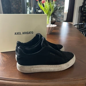 Svarta sneakers från Axel Arigato - Snygga svarta sneakers från Axel Arigato med en stilren design. Skorna har en vit sula som ger en fin kontrast till det svarta. Perfekta för en avslappnad och trendig look.
