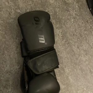 Svarta boxningshandskar - Säljer ett par svarta boxningshandskar med en stilren design. De har en bred kardborrestängning för extra stöd och komfort. Perfekta för träning och sparring. 🥊