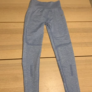 Blå leggings från ICANIWILL - Snygga blå leggings från ICANIWILL med perforerade detaljer längs benen för extra ventilation. De är högmidjade och har en tight passform, perfekta för träning. Materialet är mjukt och stretchigt för maximal komfort. Dock så har dem ett litet hål på benet och ett litet hål på grenen.⭐️👖