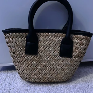 Flätad shoppingväska med svarta detaljer från Gina Tricot - Snygg flätad shoppingväska med svarta handtag och kant. 